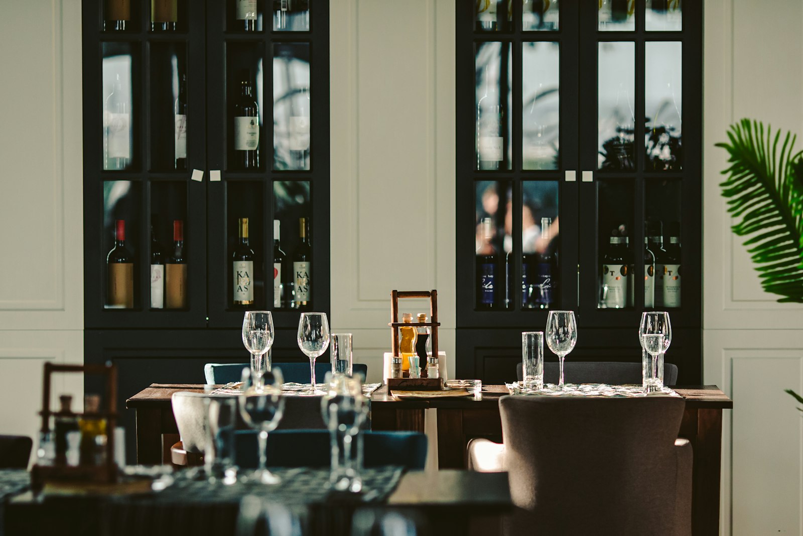 A set dining table in front of dark wine cabinets